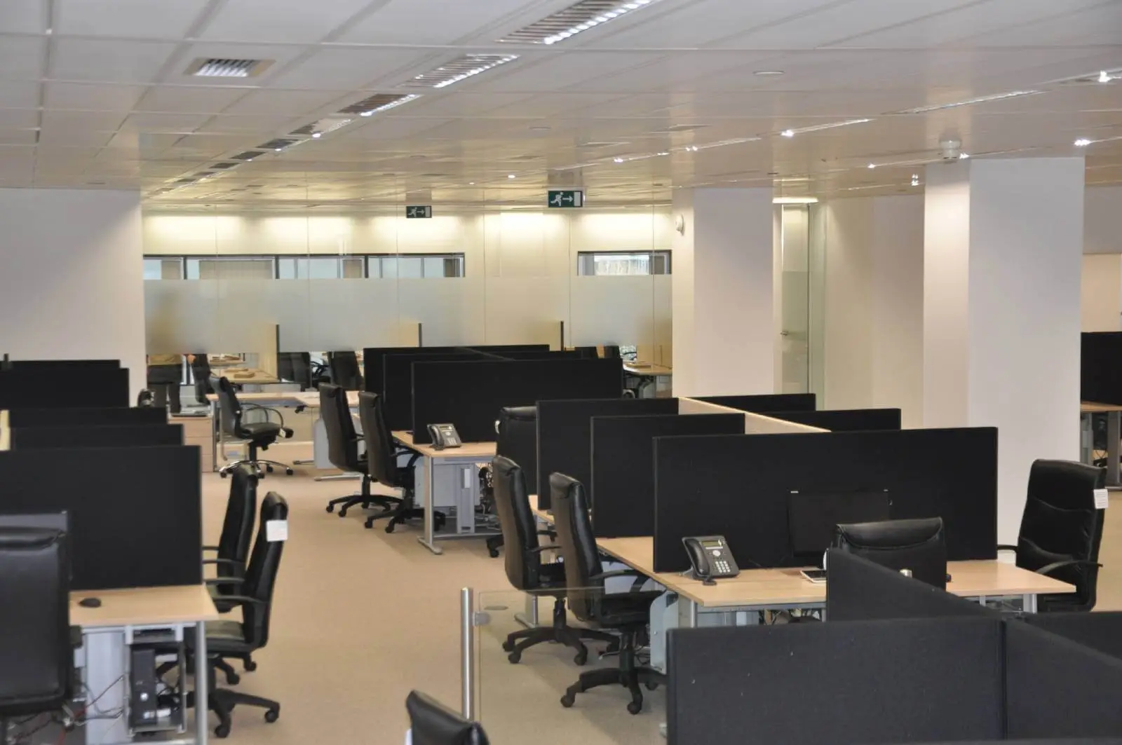 Bordeux office space with designer furniture, laminated wood floor, suspended grid ceiling, and glass partitions