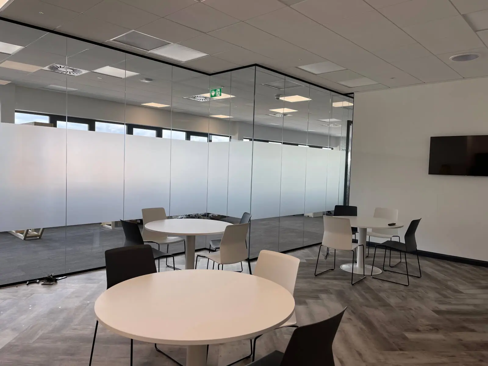 EFL office space with designer back to back desks, chairs, laminated wood flooring, suspended grid ceiling and glass partitions 10