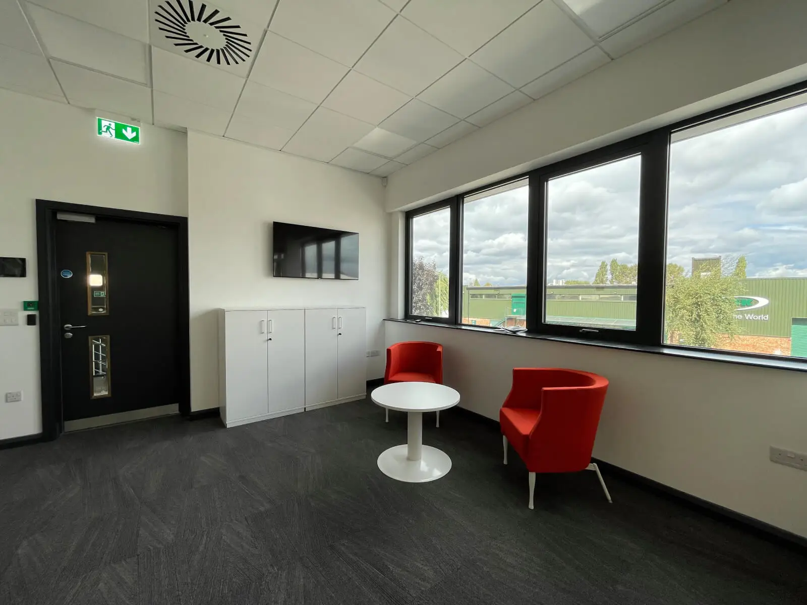 EFL office space with designer back to back desks, chairs, laminated wood flooring, suspended grid ceiling and glass partitions 12