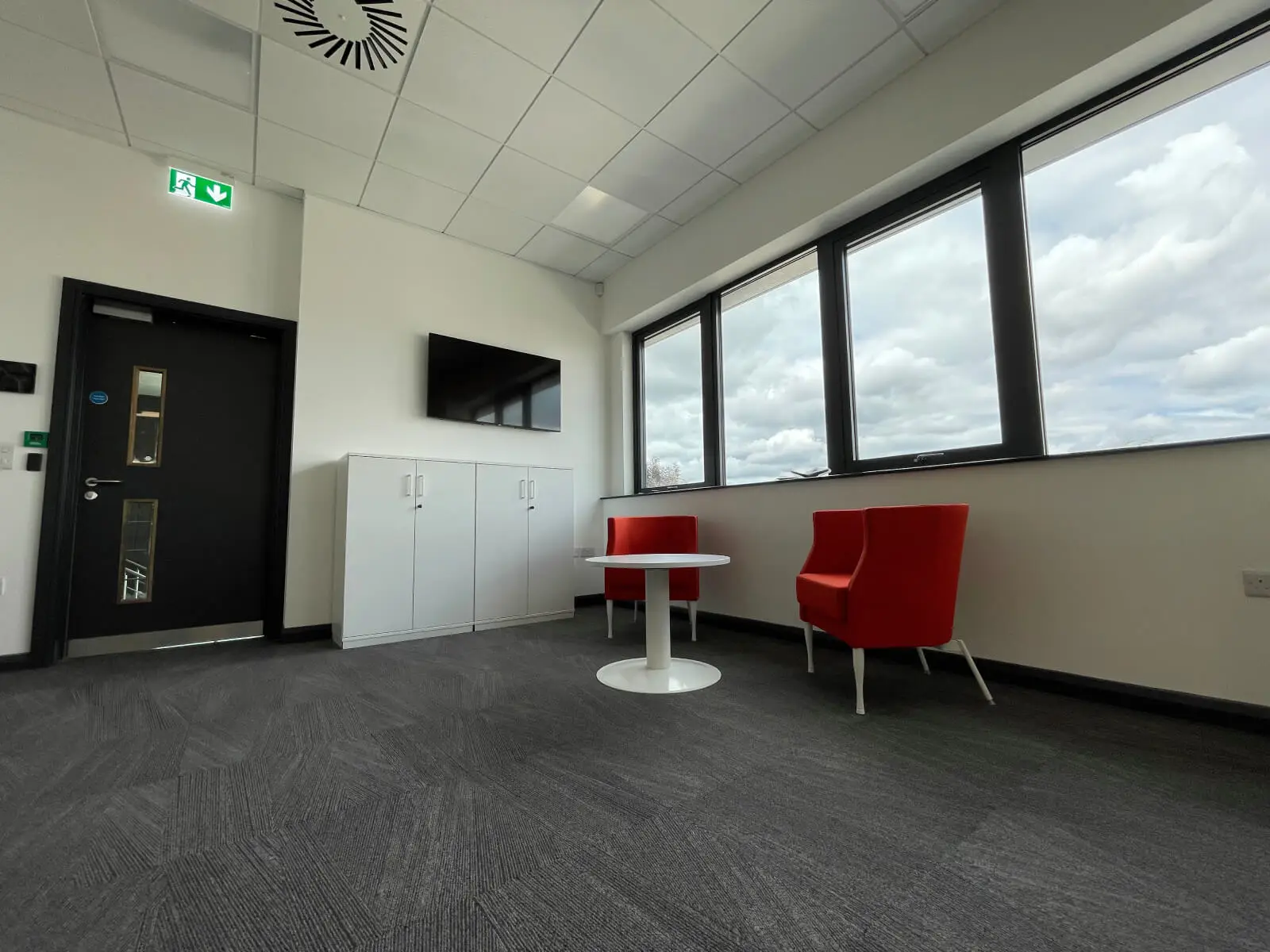 EFL office space with designer back to back desks, chairs, laminated wood flooring, suspended grid ceiling and glass partitions 13