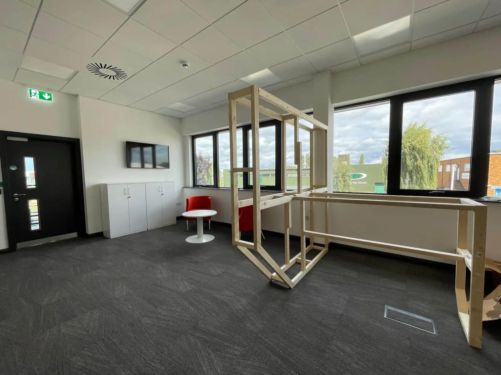 EFL office space with designer back to back desks, chairs, laminated wood flooring, suspended grid ceiling and glass partitions 14