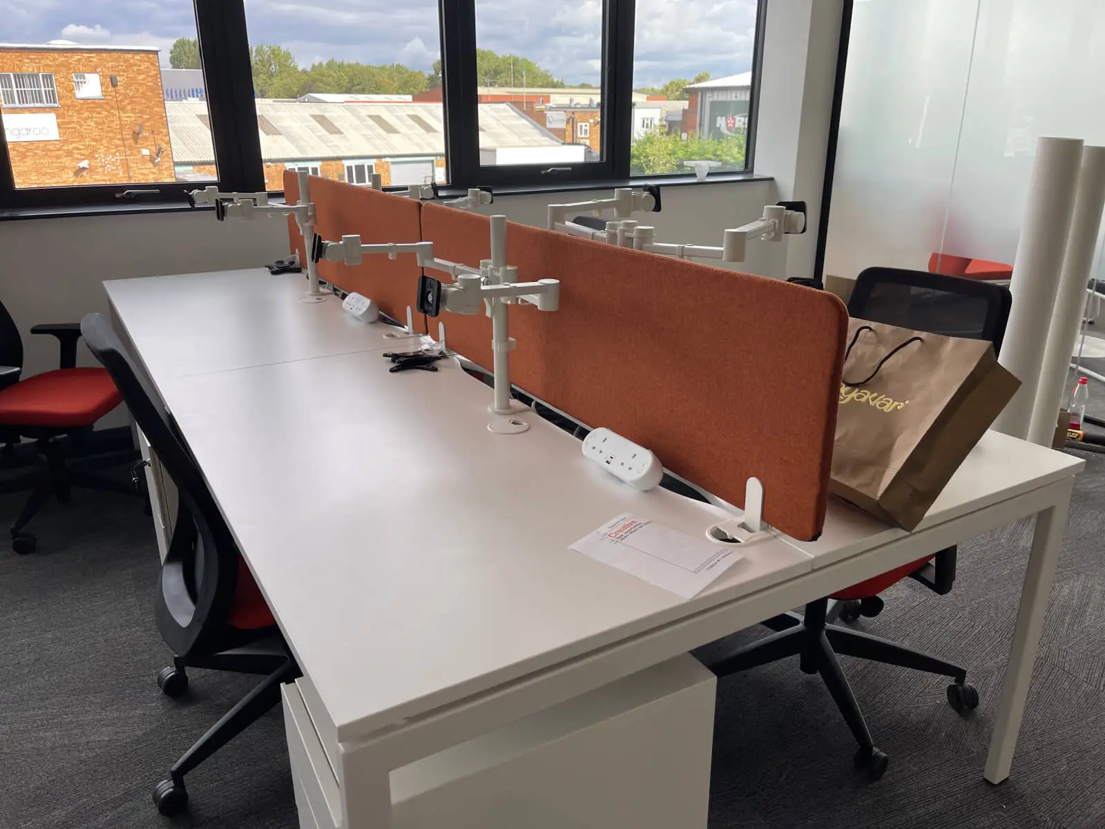 EFL office space with designer back to back desks, chairs, laminated wood flooring, suspended grid ceiling and glass partitions 17