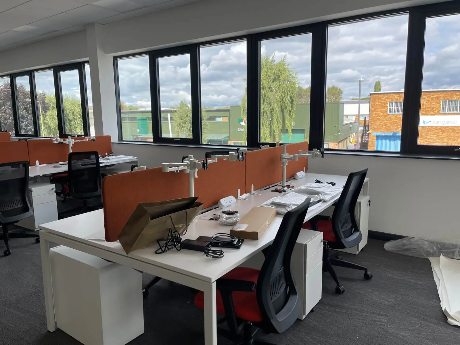 EFL office space with designer back to back desks, chairs, laminated wood flooring, suspended grid ceiling and glass partitions 18