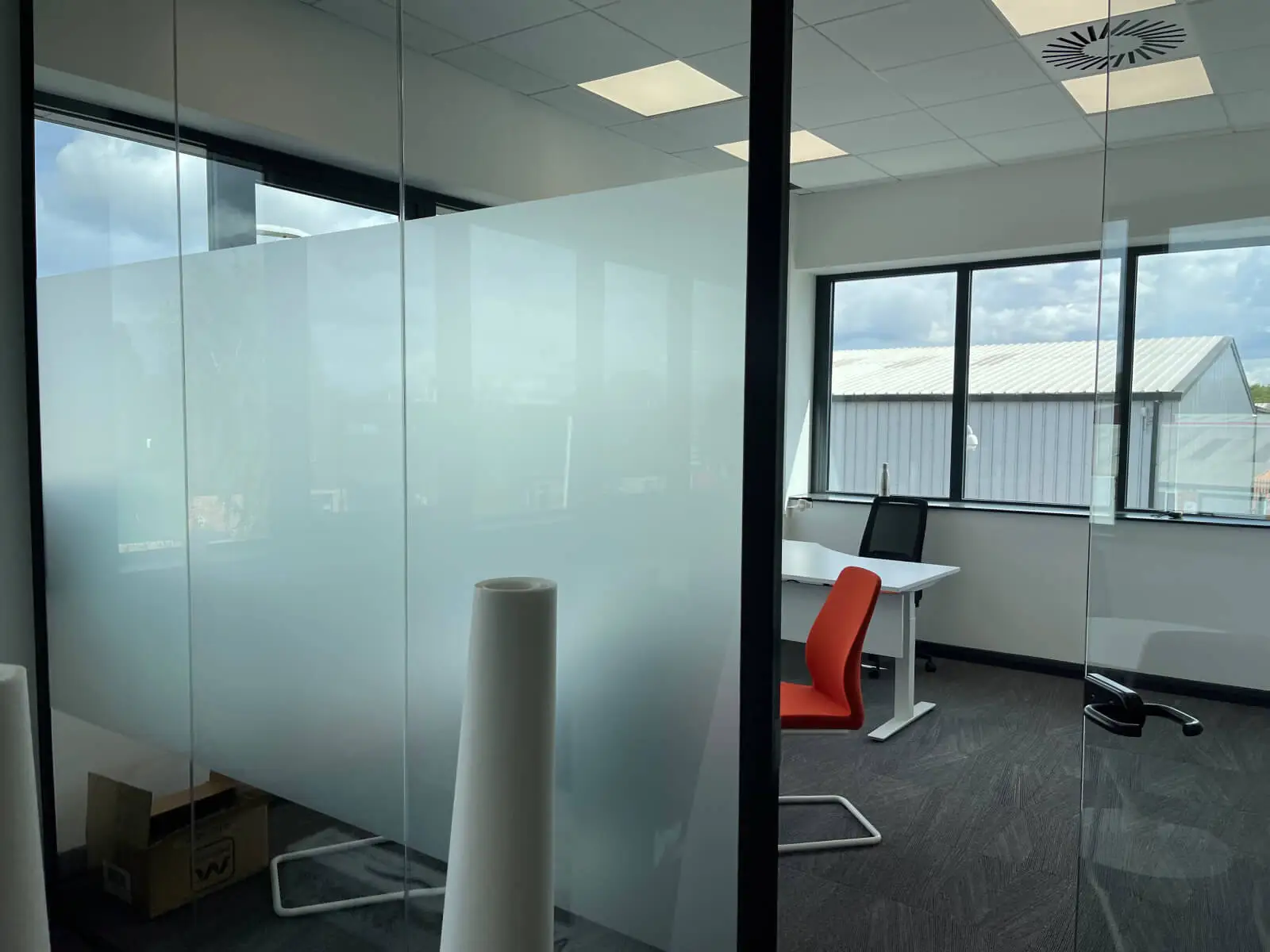 EFL office space with designer back to back desks, chairs, laminated wood flooring, suspended grid ceiling and glass partitions 20