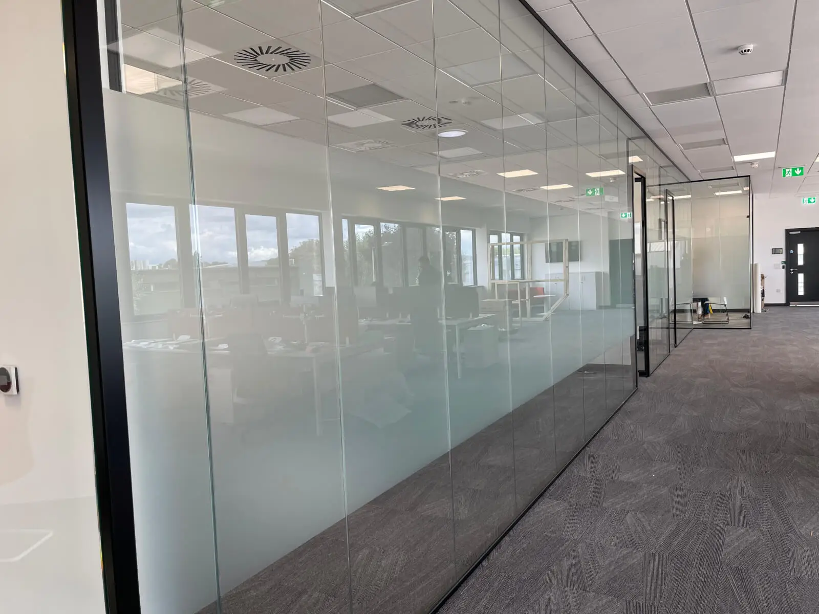 EFL office space with designer back to back desks, chairs, laminated wood flooring, suspended grid ceiling and glass partitions 25