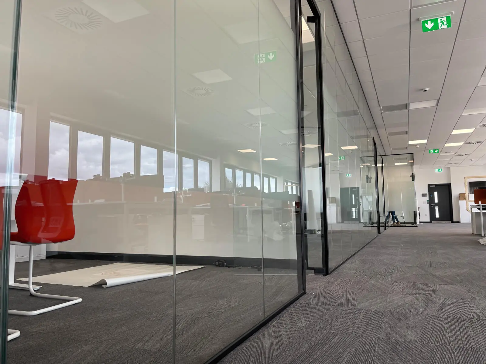 EFL office space with designer back to back desks, chairs, laminated wood flooring, suspended grid ceiling and glass partitions 27