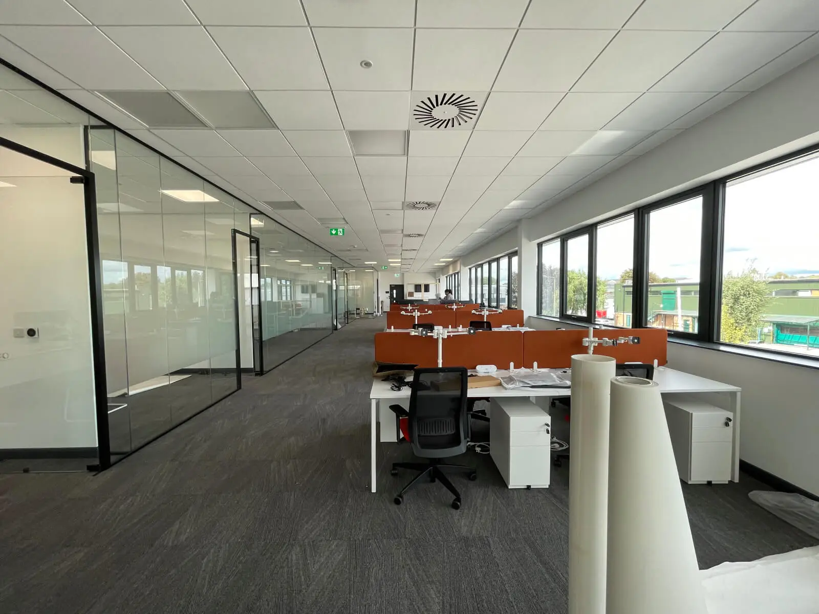 EFL office space with designer back to back desks, chairs, laminated wood flooring, suspended grid ceiling and glass partitions 28