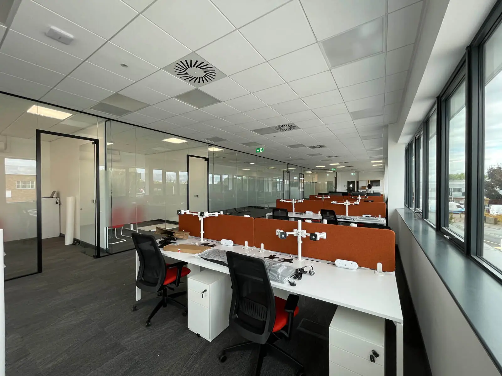 EFL office space with designer back to back desks, chairs, laminated wood flooring, suspended grid ceiling and glass partitions 29