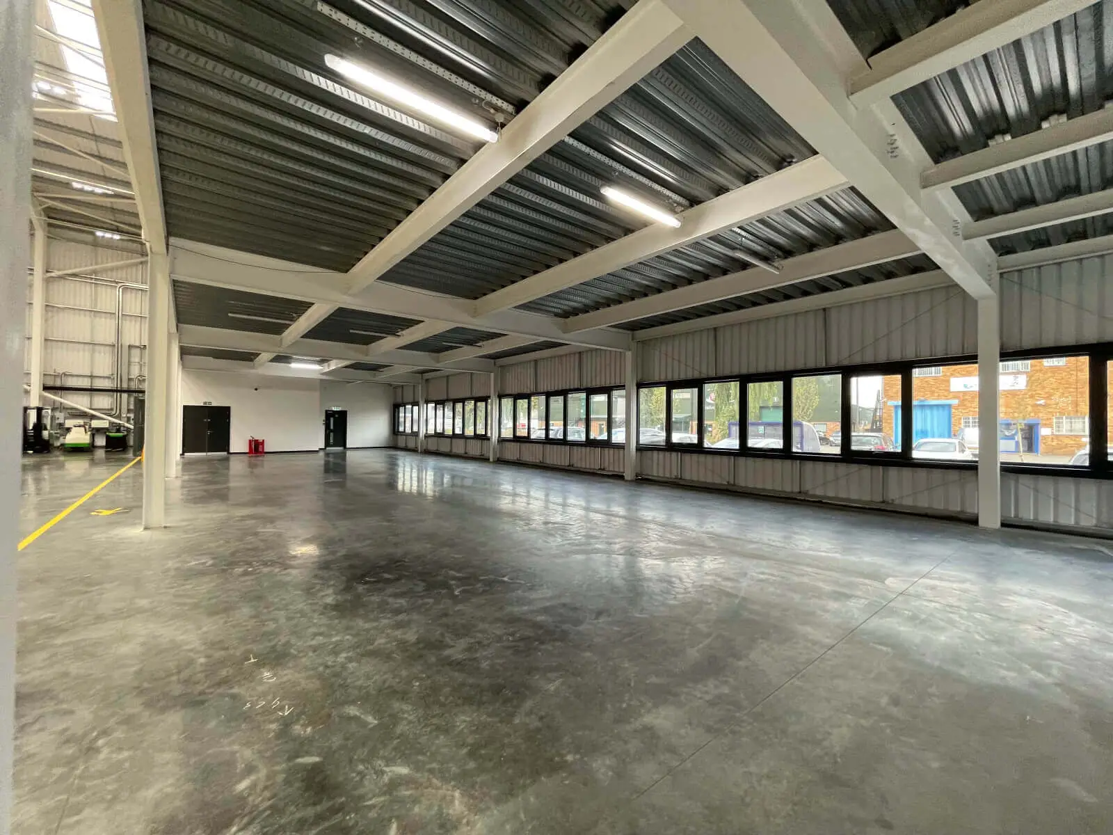 EFL office space with designer back to back desks, chairs, laminated wood flooring, suspended grid ceiling and glass partitions 31