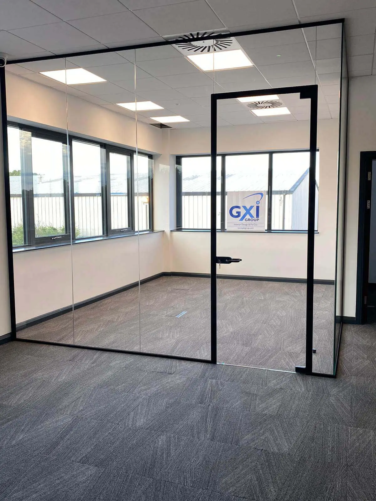 EFL office space with designer back to back desks, chairs, laminated wood flooring, suspended grid ceiling and glass partitions 35