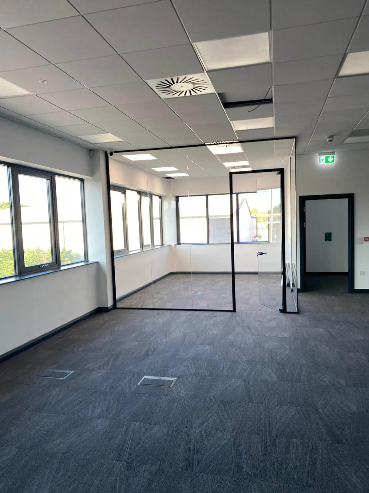 EFL office space with designer back to back desks, chairs, laminated wood flooring, suspended grid ceiling and glass partitions 36