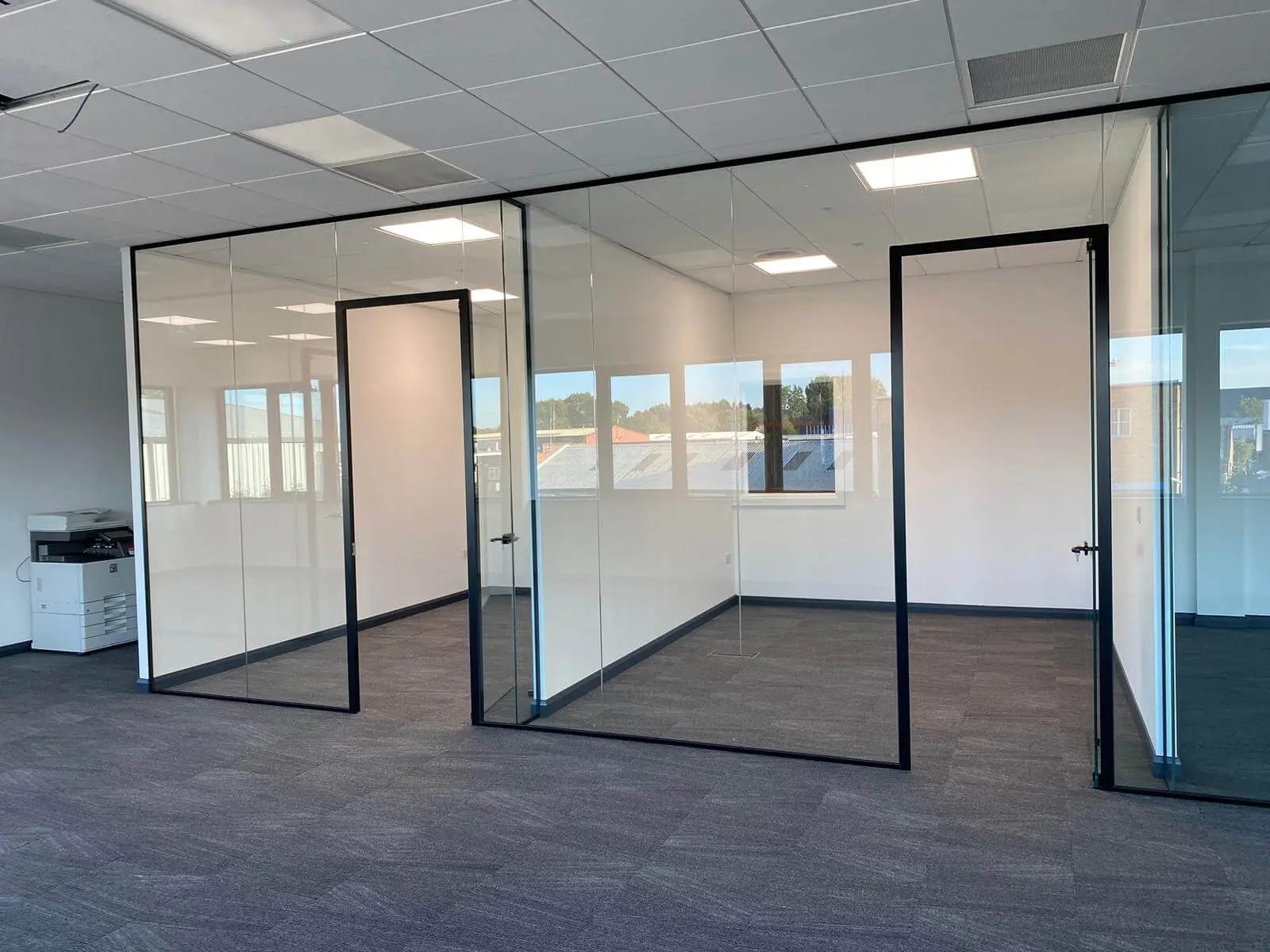 EFL office space with designer back to back desks, chairs, laminated wood flooring, suspended grid ceiling and glass partitions 41
