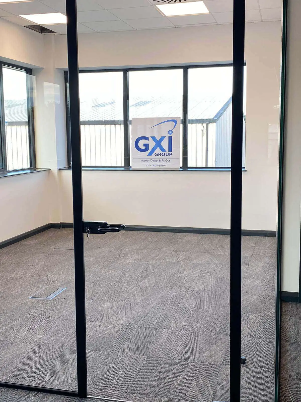 EFL office space with designer back to back desks, chairs, laminated wood flooring, suspended grid ceiling and glass partitions 44