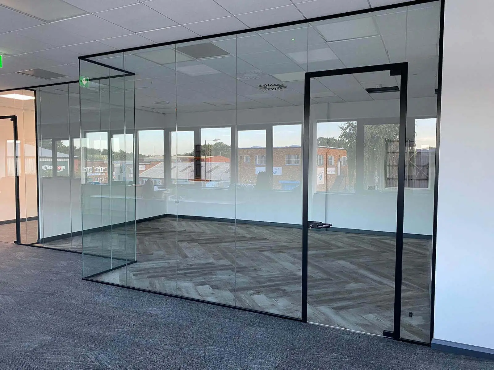 EFL office space with designer back to back desks, chairs, laminated wood flooring, suspended grid ceiling and glass partitions 45