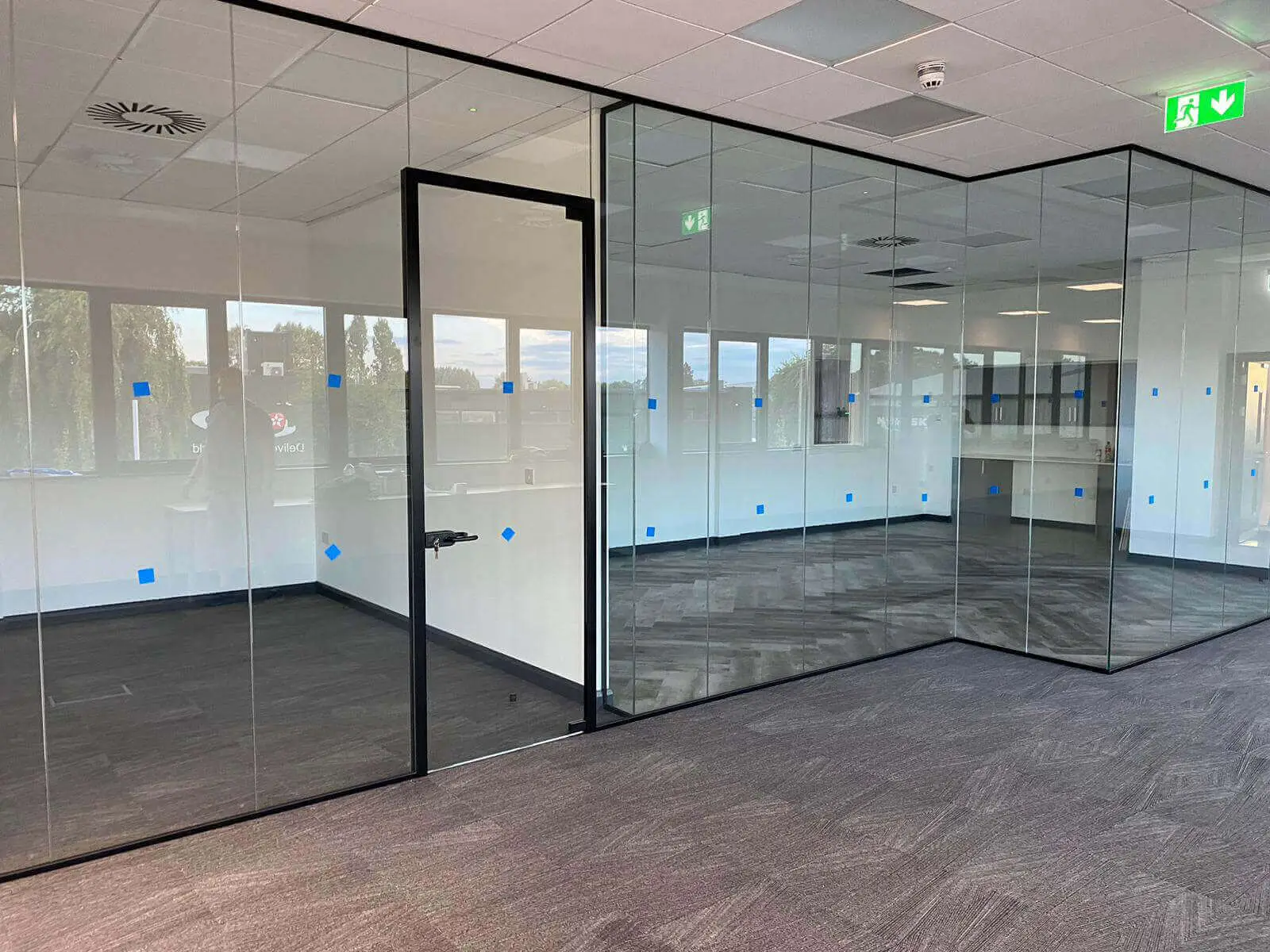 EFL office space with designer back to back desks, chairs, laminated wood flooring, suspended grid ceiling and glass partitions 46