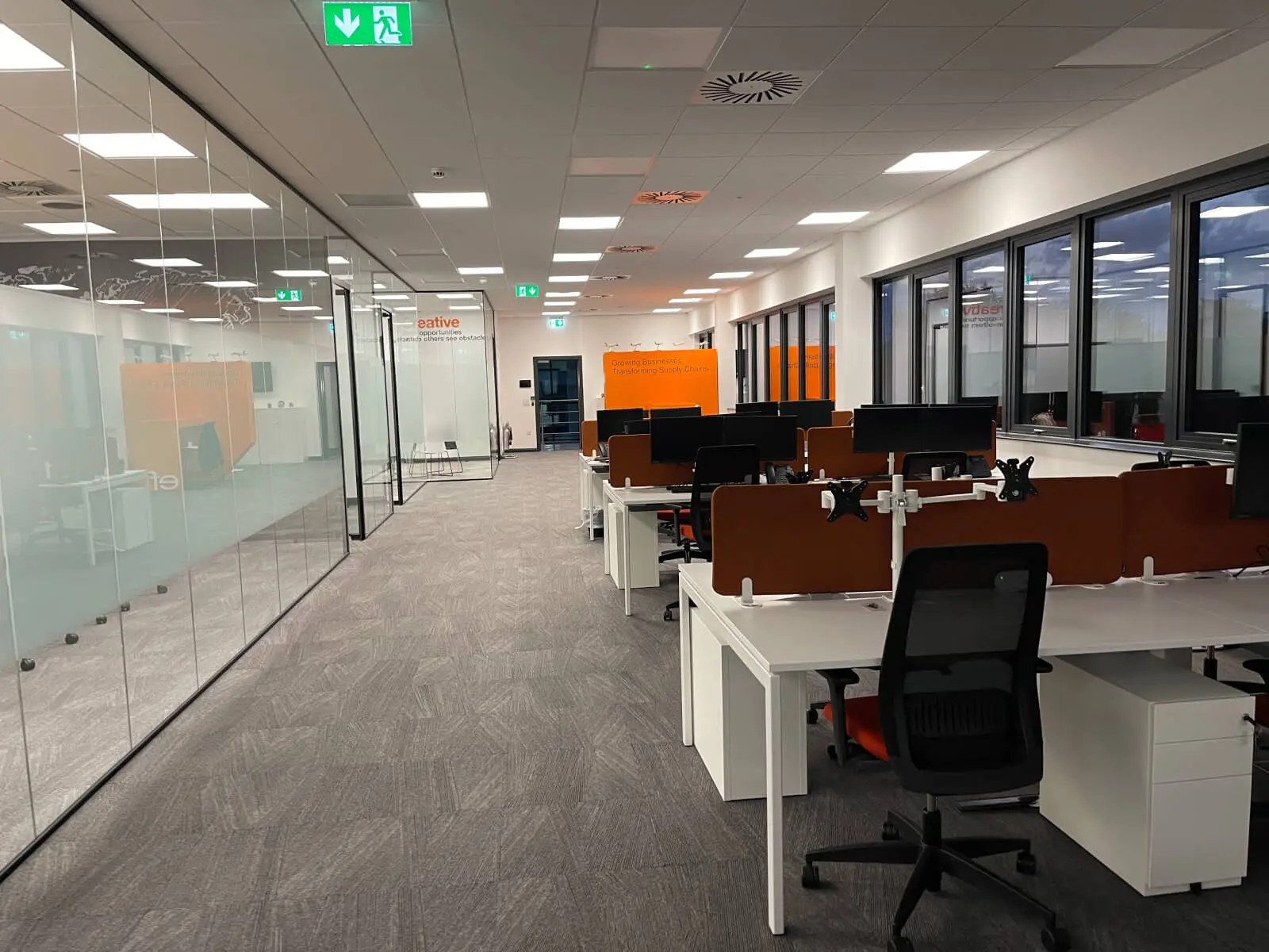 EFL office space with designer back to back desks, chairs, laminated wood flooring, suspended grid ceiling and glass partitions 5