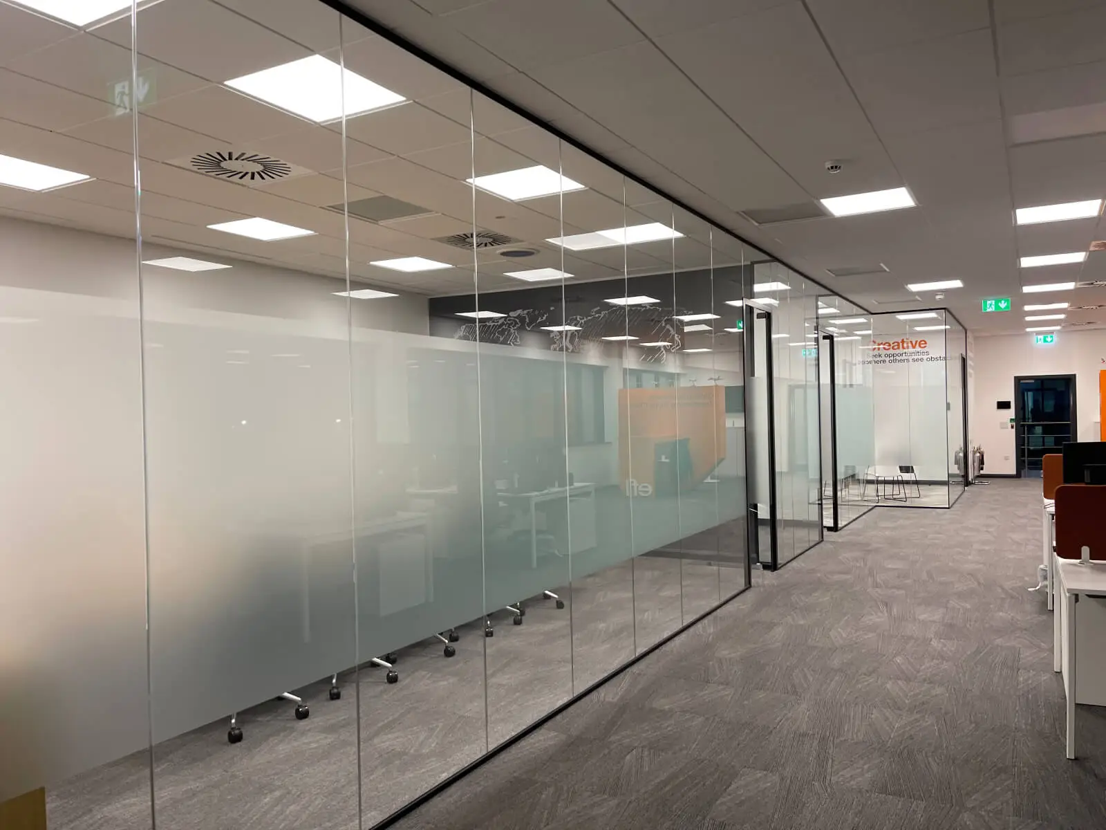 EFL office space with designer back to back desks, chairs, laminated wood flooring, suspended grid ceiling and glass partitions 6
