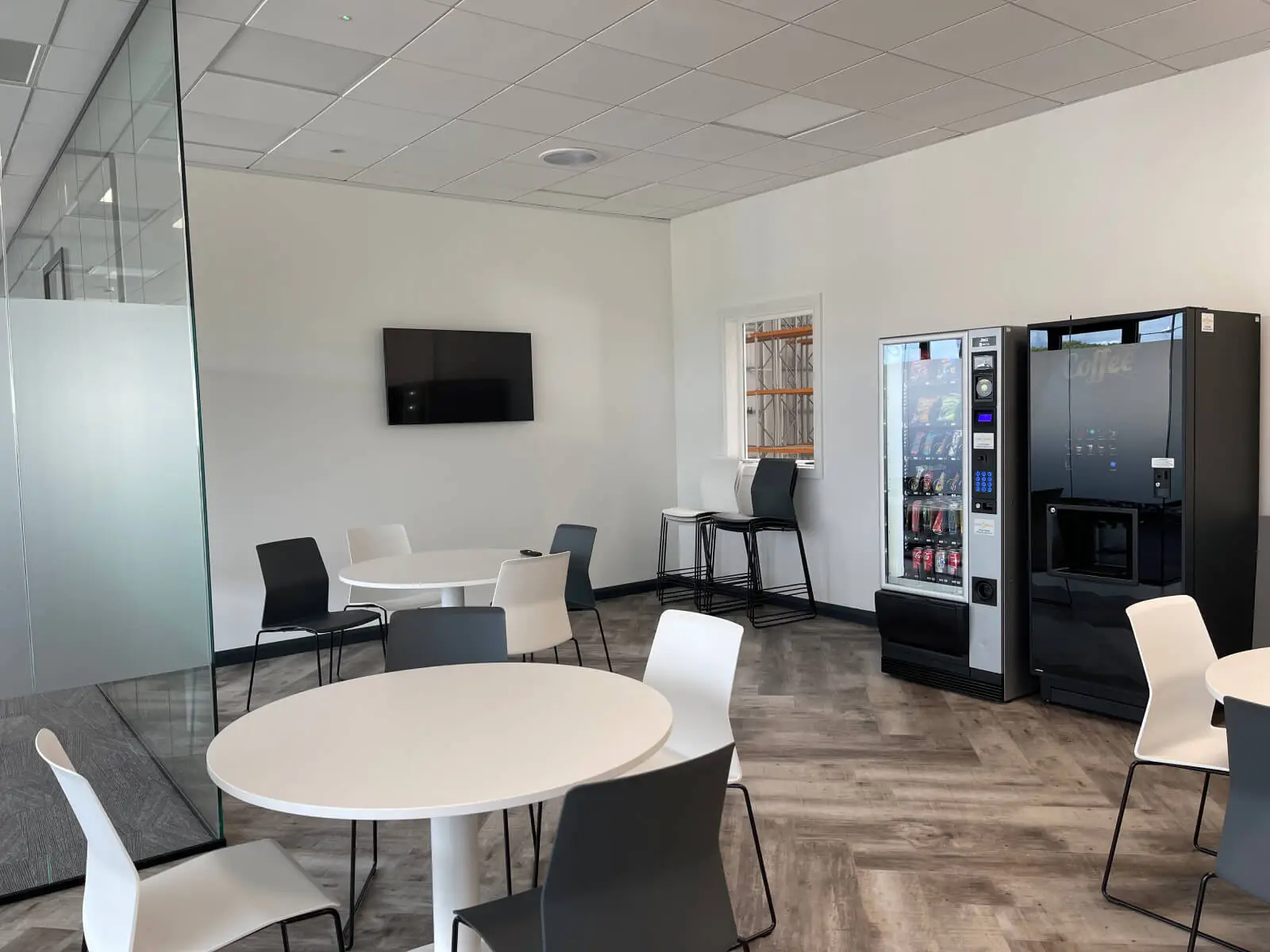 EFL office space with designer back to back desks, chairs, laminated wood flooring, suspended grid ceiling and glass partitions 9