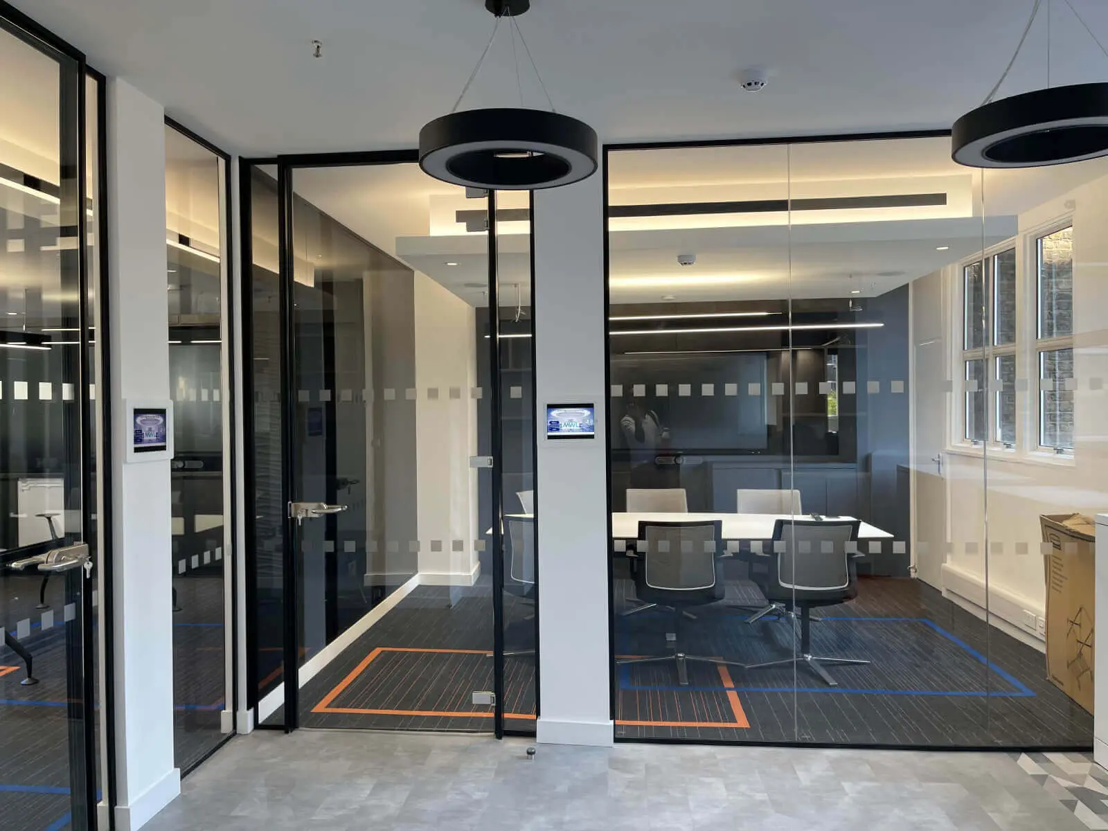 Mendik Waring office space design with designer flooring, acoustic ceiling and black framed glass partitions 3
