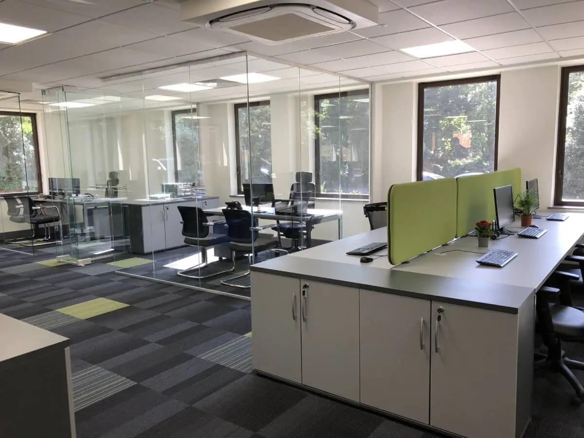 Office space with desks chairs storages and glass partitions