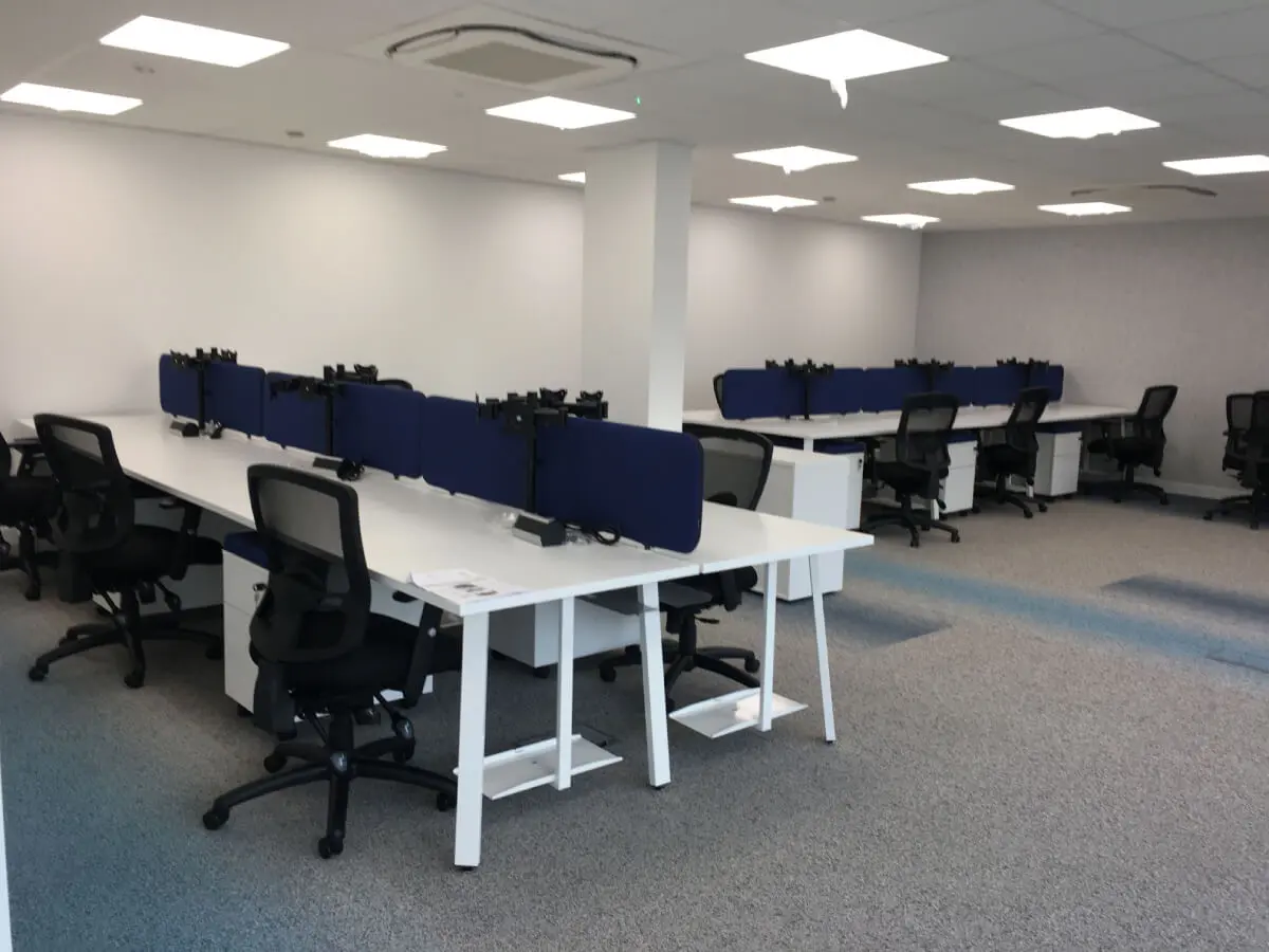 Back to back office desks with dividing screens and chairs