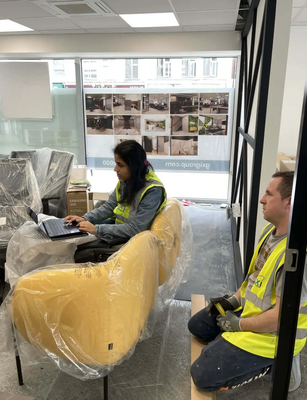 GXI team member working on laptop seating on a chair