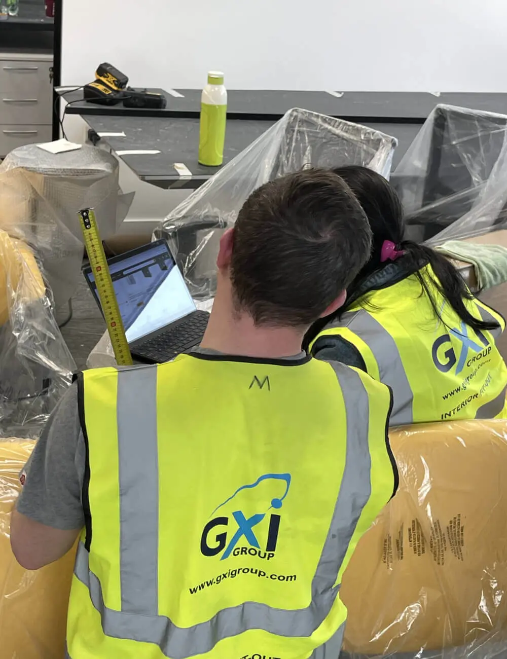 GXI team members looking at laptop at office refurbishment site